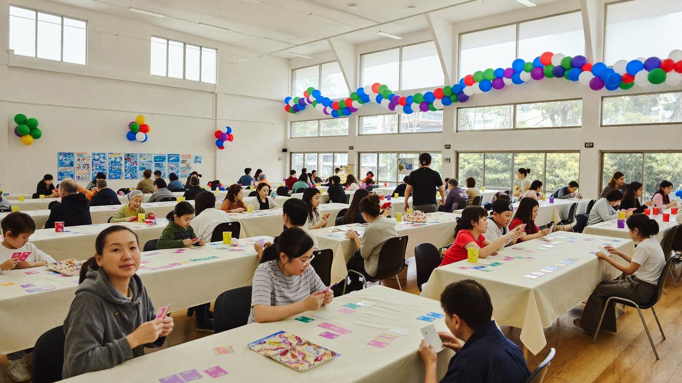 複数のテーブルで家族がカードゲームを楽しむ会場